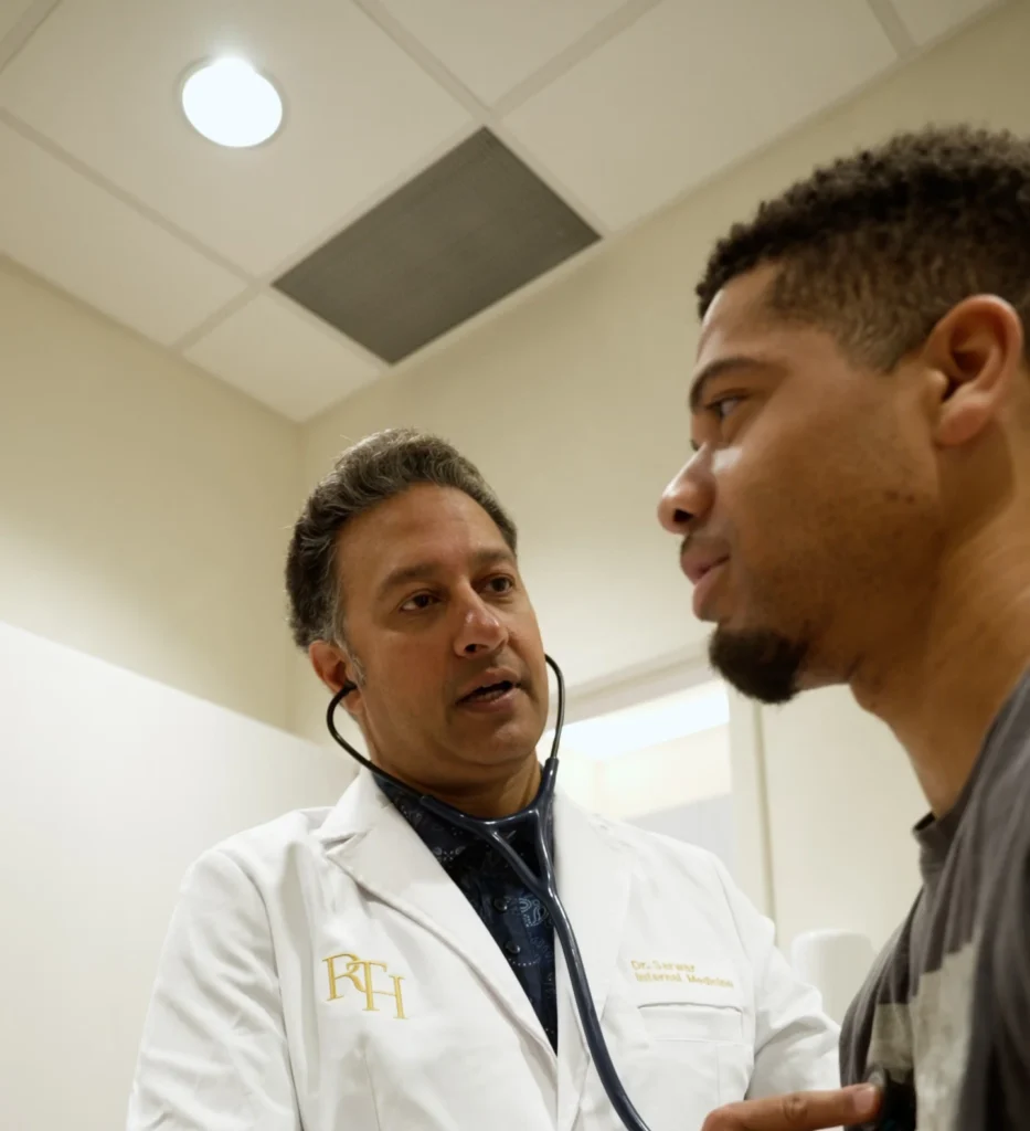 Internal medicine physician in an RTH coat speaking with a patient